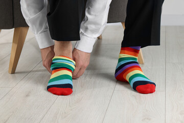 Man putting on colorful socks indoors, closeup