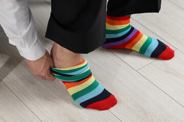 Man putting on colorful socks indoors, closeup