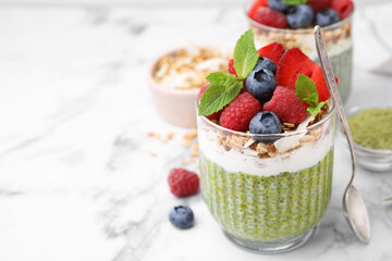 Tasty matcha chia pudding with oatmeal and berries on white marble table, closeup. Space for text. Healthy breakfast