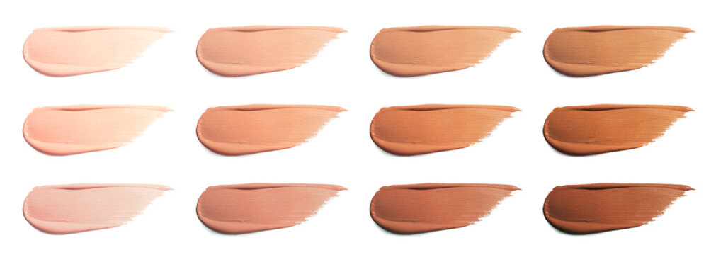 Different shades of liquid skin foundation on white background, top view. Set with samples of makeup product