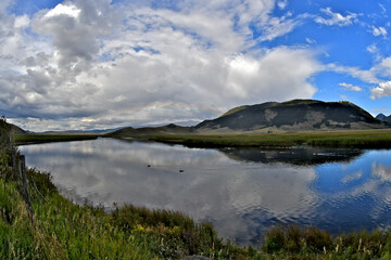 The slow moving Flat Creek provides mirror like flatness reflecting clouds, Jackson, Wyoming
