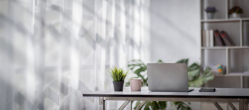 Laptop Computer, notebook, and eyeglasses sitting on a desk in a large open plan office space after working hours	