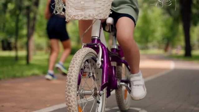 close-up of children's legs on pedals riding a bicycle in the park childhood active lifestyle