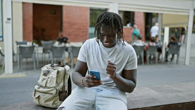 African american man dancing listening to music on smartphone at coffee shop terrace