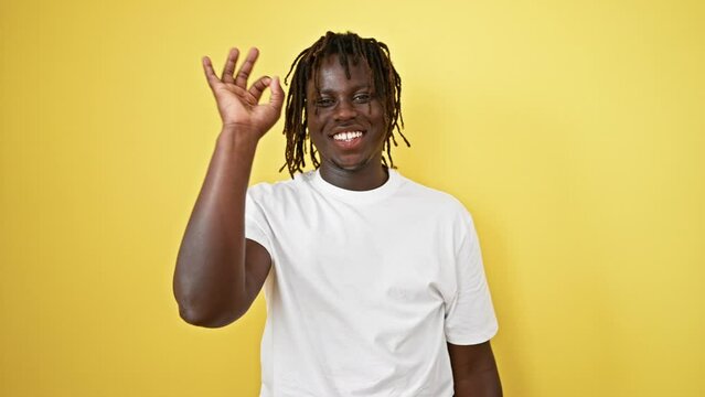African american man doing ok gesture smiling over isolated yellow background