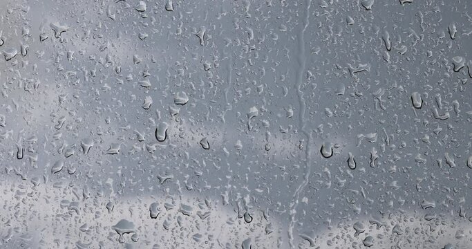glass with water drops during rain, glass covered with rain water drops in a building window