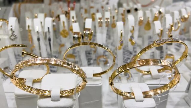 Women's gold bracelets in a jewelry store window. Close-up