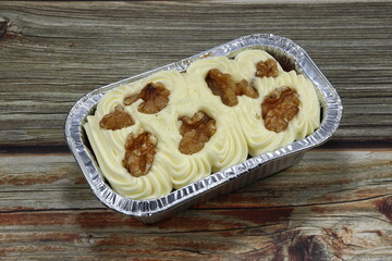 Traditional baked carrot cake topping with pecan nut serving in the foil packaging. Famous classic sweet dessert menu in bakery shop. 