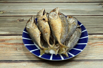 Pile of deep fried fresh mackerel fish serving on the plate. Famous traditional seafood menu in Thai restaurant. Mock up of salty seafood product in the local market concept. 
