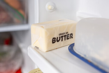 A view of a stick of butter package on a refrigerator door shelf.