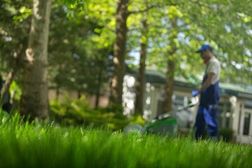 Fototapeta premium Professional garden worker, working with electric lawn mower on grass