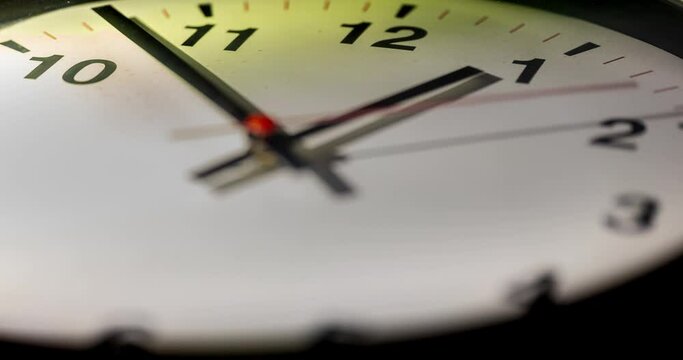 Close-up time lapse of a  modern wall clock with roman numerals on the clock face. Selective focus on the numbers. The seconds pointer overtake the minutes frequently. Counting down the time