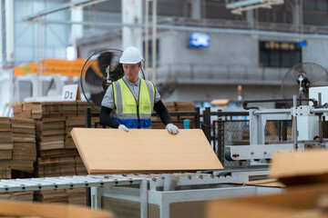 A male employee is using a machine to sew cardboard boxes in a warehouse. and arrange cardboard...