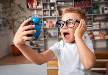 School boy dreaming with alarm clock in classroom