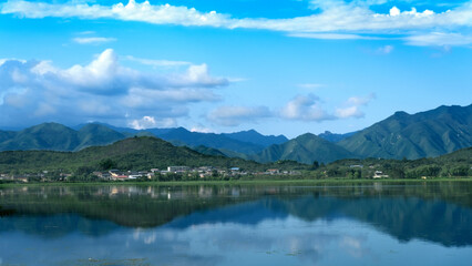 Naklejka na ściany i meble white clouds,blue sky,blue lake,green plants and green mountains. 