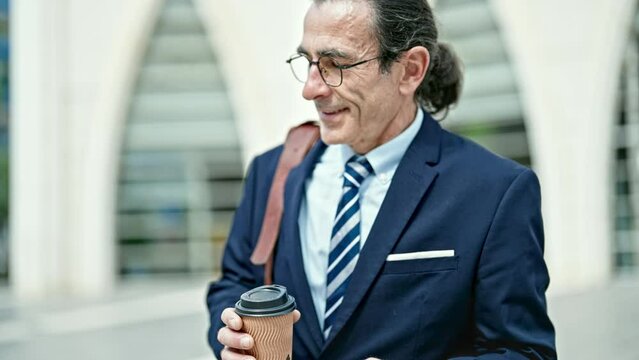 Middle age man business worker holding coffee using smartphone at hospital