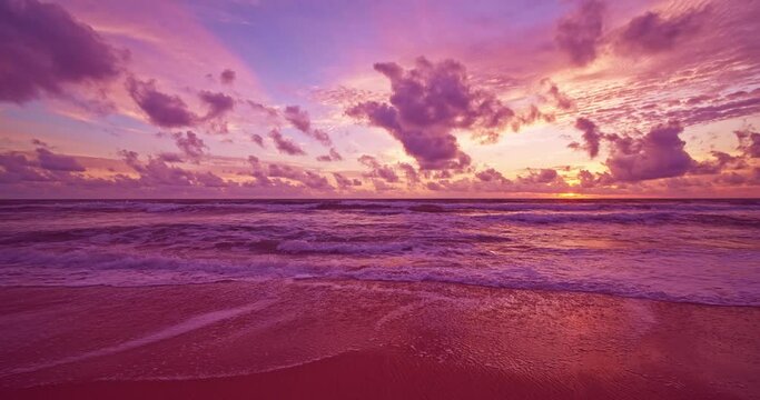 Colorful ocean beach at sunrise or sunset sky over sea,Beautiful waves crashing on pink sandy shore in summer season,Slow motion waves sea beach background