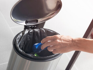 Man hand drop of a garbage bin in the outside park Crumpled plastic can recycle  into basket. as...