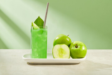 Delicious green apple juice filled in a glass. Fresh green apples displayed next to it on white dish. Green Apple (Malus domestica) contains a lot of fiber and minerals