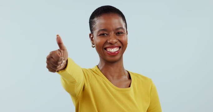 Success, smile and thank you with a black woman thumbs up in studio on a blue background for motivation. Portrait, goal and happy with a winner young person showing a like emoji to gesture yes