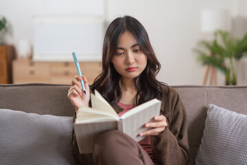 Women leisure on sofa to thinking about something and writing down on notebook in lifestyle at home