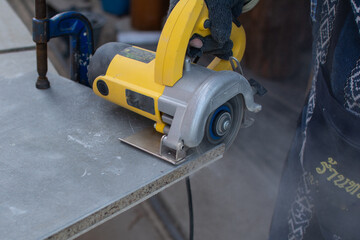 Worker using a grinding machine for cut cement board.