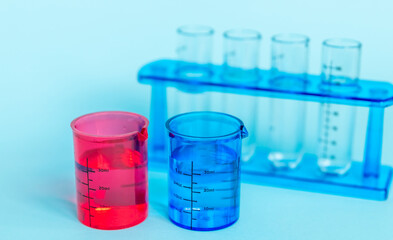 A set of various laboratory glassware and liquids for analysis on a blue background. Flasks and test tubes of different colors. A visual aid for studying chemistry and medicine. School plastic aids.