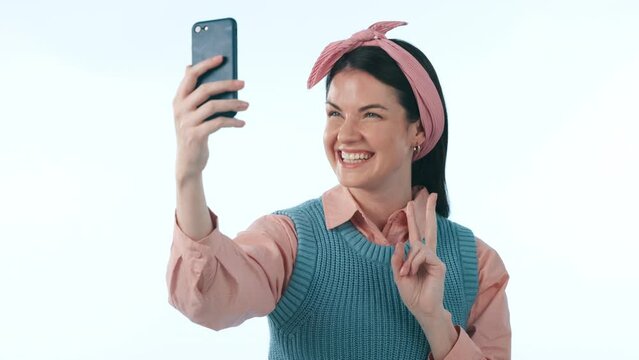 Happy, social media and peace sign selfie with a woman in studio on blue background for a profile picture. Phone, smile and photo with a young influencer or content creator posing for a status update