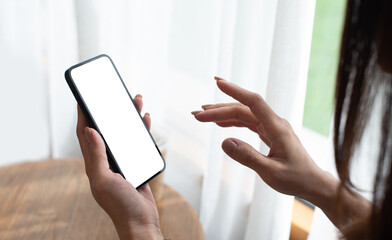 Young woman hands holding cell phone touching finger on mockup white blank display, empty screen...