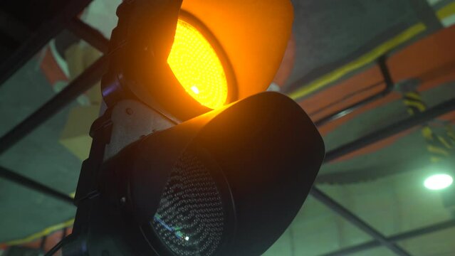 Close-up shot of an alert yellow flashing light of a traffic light or semaphore at night city 4K