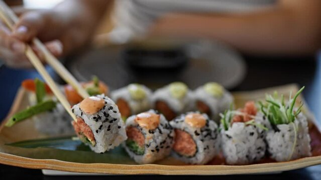 Young beautiful hispanic woman eating sushi at the restaurant