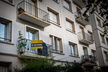 'A vendre' écrit en Français sur une enseigne jaune fixée à l'extérieur d'un appartement dans un immeuble résidentiel. Concept de marché immobilier d'habitation en France