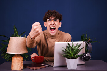 Funny curly guy working at a laptop. Blue background.