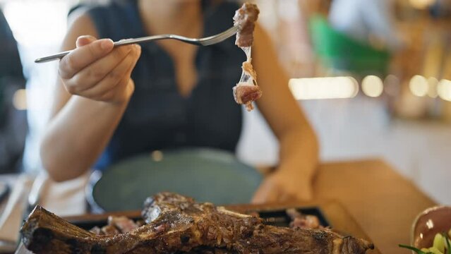 Young beautiful hispanic woman eating meat from steak at the restaurant
