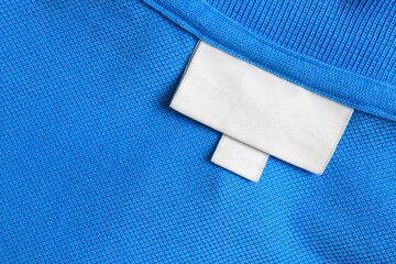 Blank white laundry care clothes label on blue shirt fabric texture background