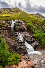 Stunning scenery with high mountains and three waterfalls converging in the Glencoe Valley, Scotland.