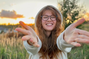 Portrait of happy young woman in glasses at sunset on natural background smile and looking at camera. 