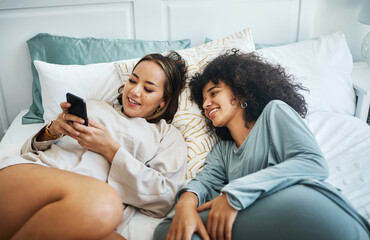 Phone, social media and a lesbian couple in bed together in the morning for communication or to relax. Love, lgbt and a woman watching a movie or video with her girlfriend in the home bedroom - obrazy, fototapety, plakaty