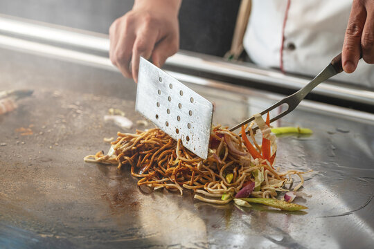 Teppanyaki chef preparing food on hot metal plate