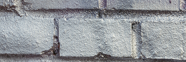 Old brick wall painted in silver color. Texture of rough brickwork. Wide panoramic background with masonry.