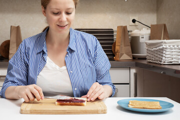 woman making classic american sandwich, spreading raspberry jam on toast bread, quick lunch
