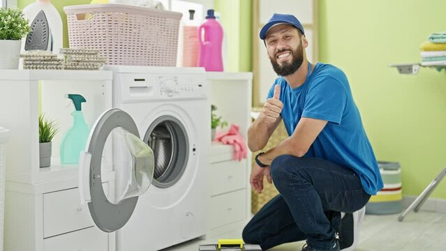 Young hispanic man technician holding toolbox doing thumb up gesture at laundry room