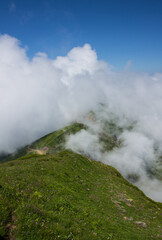 beautiful panoramic landscape - mountain peaks through white clouds against the blue sky on a sunny day and copy space