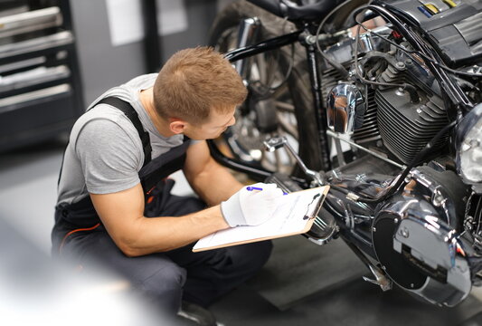 Foreman in service repair center diagnoses parts on motorcycle. Service and warranty service of concept motorcycles