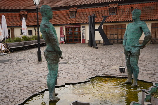 PRAGUE, CZECH REPUBLIC - July 7, 2023. The Piss sculpture by Czech artist David Cerny with two animatronic figures piddling in a puddle in front of Franz Kafka Museum in Prague.