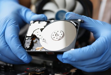 Gloved master holds computer hard drive. Computer equipment repair and maintenance concept - obrazy, fototapety, plakaty