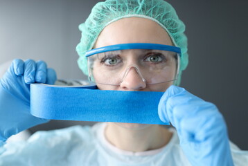 Woman doctor sealing her mouth with blue tape. Medical secrecy concept