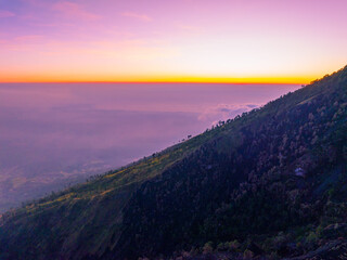 Amazing Sunset or sunrise landscape with high peaks and foggy forest under vibrant colorful sky clouds over mountains