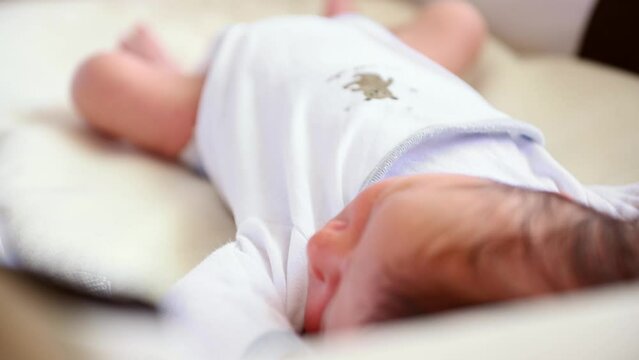 Close-up view. Newborn baby boy in the first days of life, dressed in white bodysuit, sweet sleeping in a transportable crib at home. Childbirth and childcare concept. Family values. Love. Tenderness.