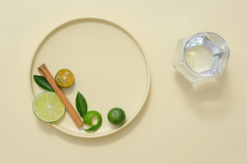 A round ceramic dishes containing slices of lime and kumquat, green leaves and dried cinnamon stick...